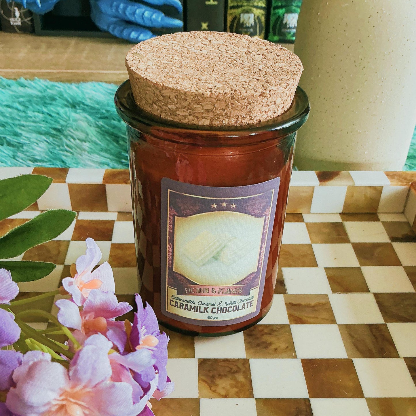 Caramilk candle on chequered board with flowers