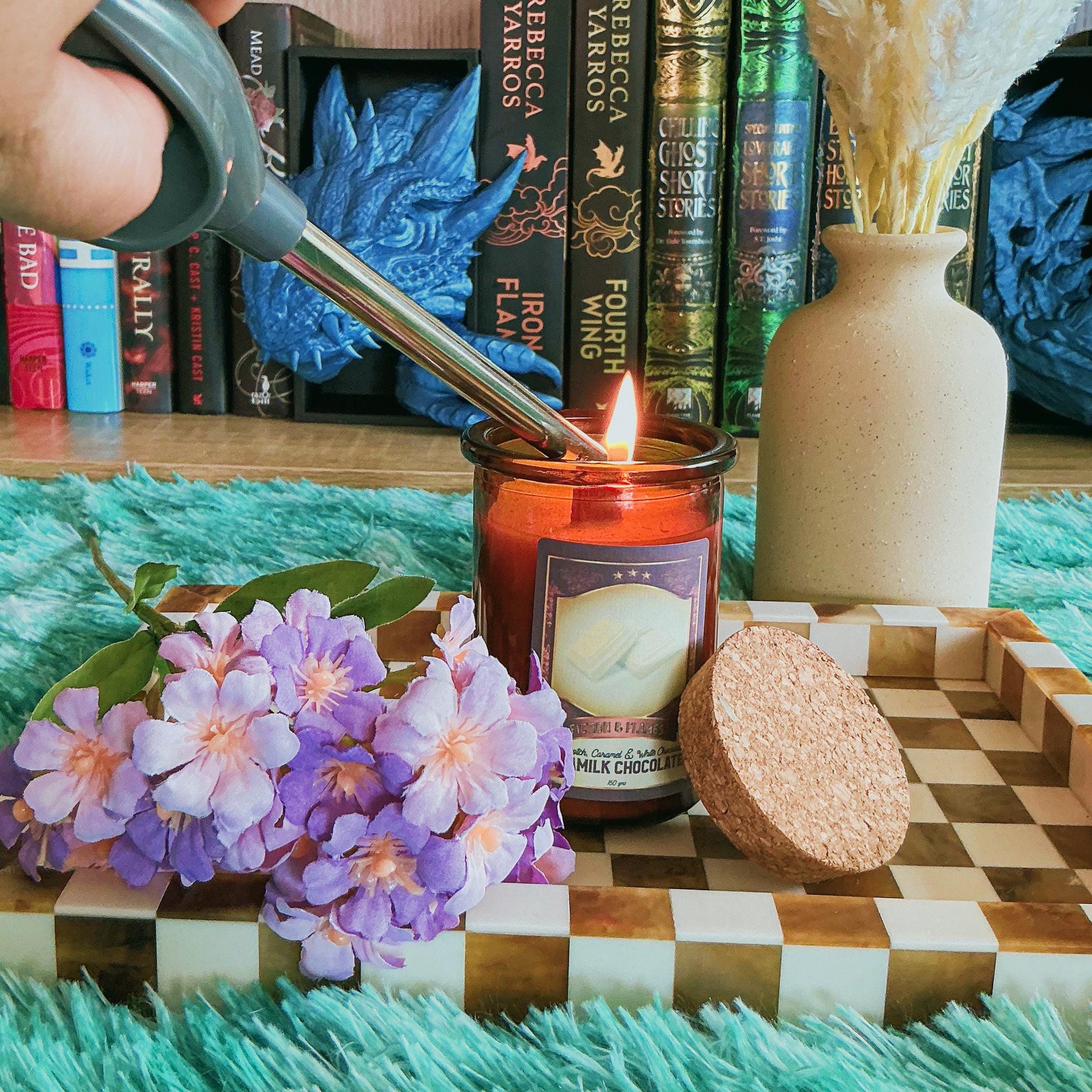Caramilk candle on chequered board with flowers