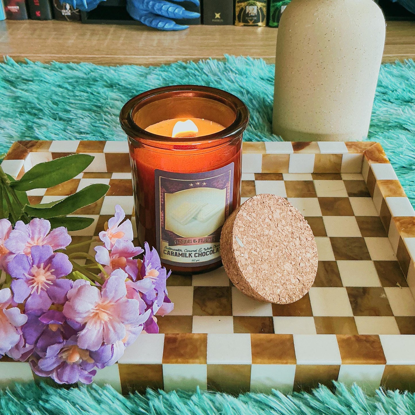 Caramilk candle on chequered board with flowers