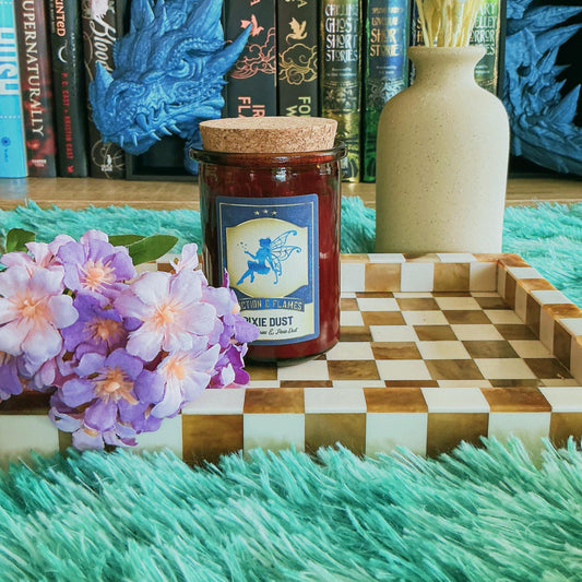 Pixie Dust Candle sitting on chequered board with flowers