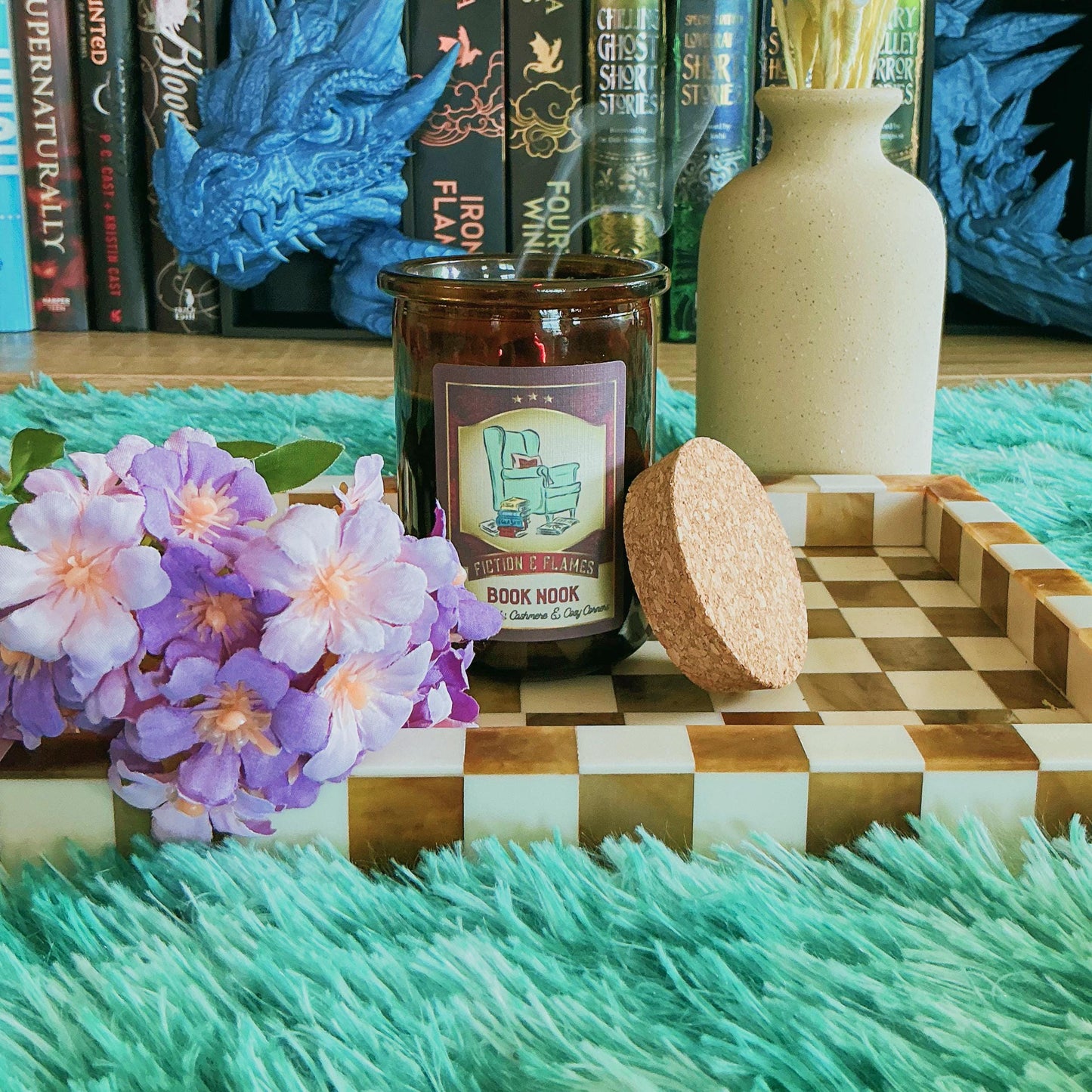 Book Nook candle on chequered board with flowers