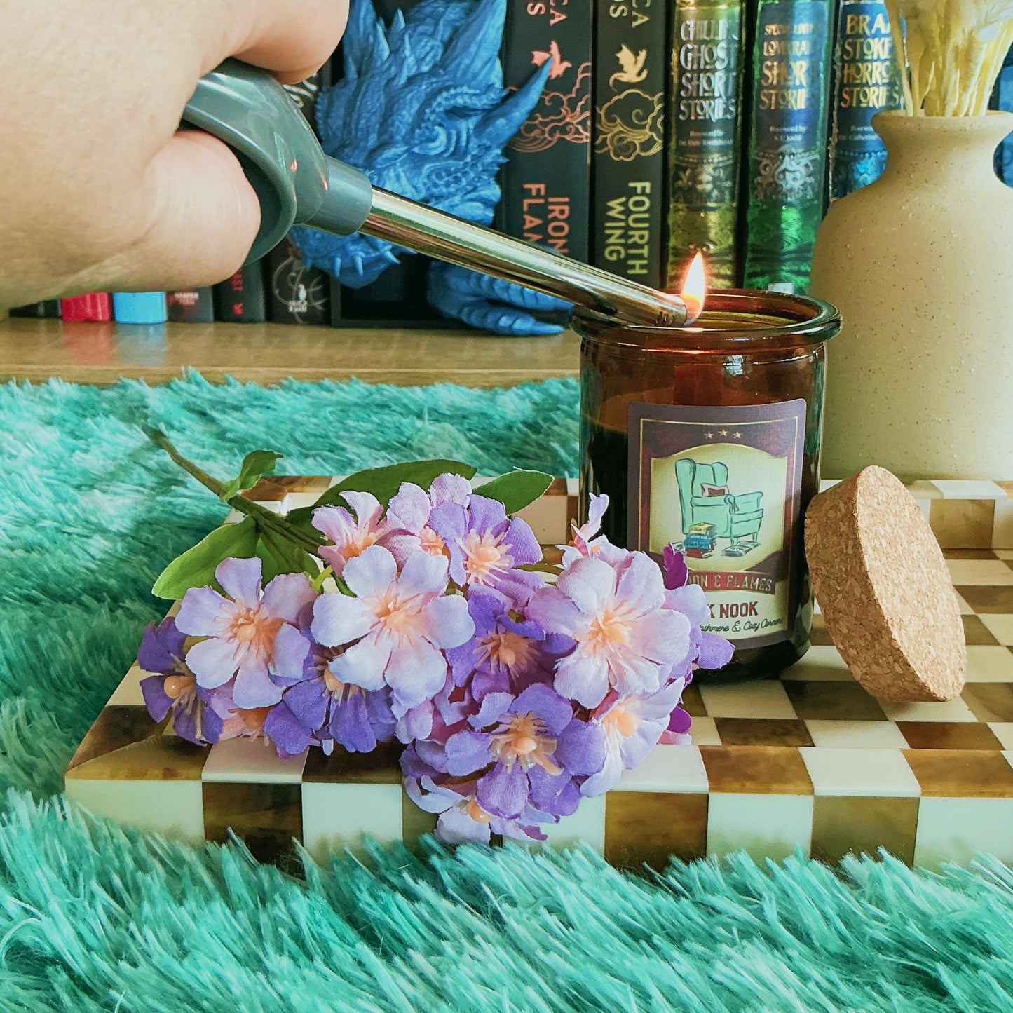 Book Nook candle on chequered board with flowers