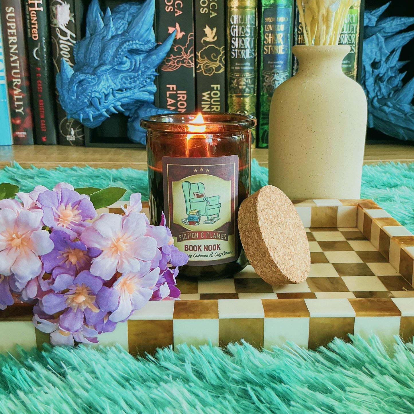 Book Nook candle on chequered board with flowers