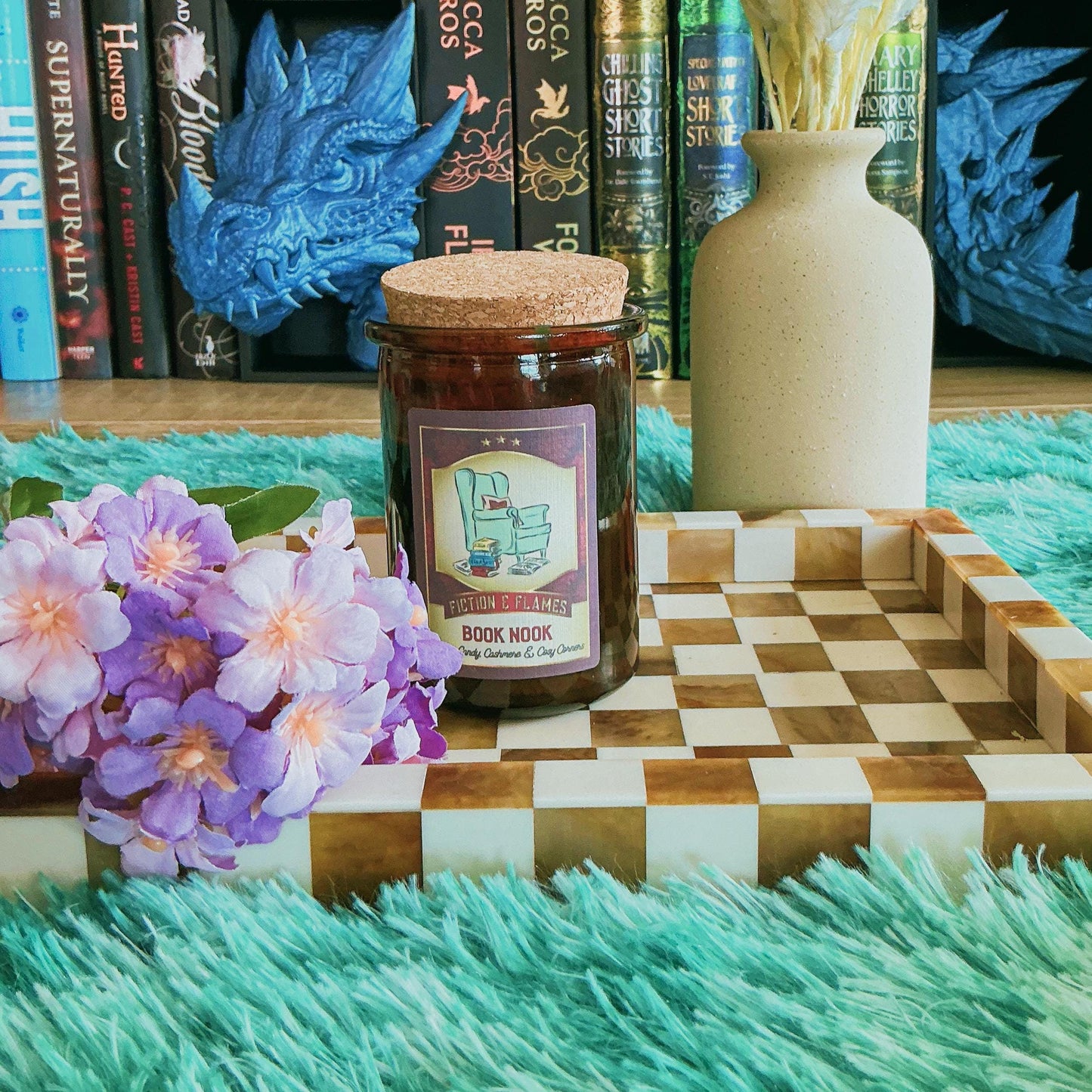 Book Nook candle on chequered board with flowers