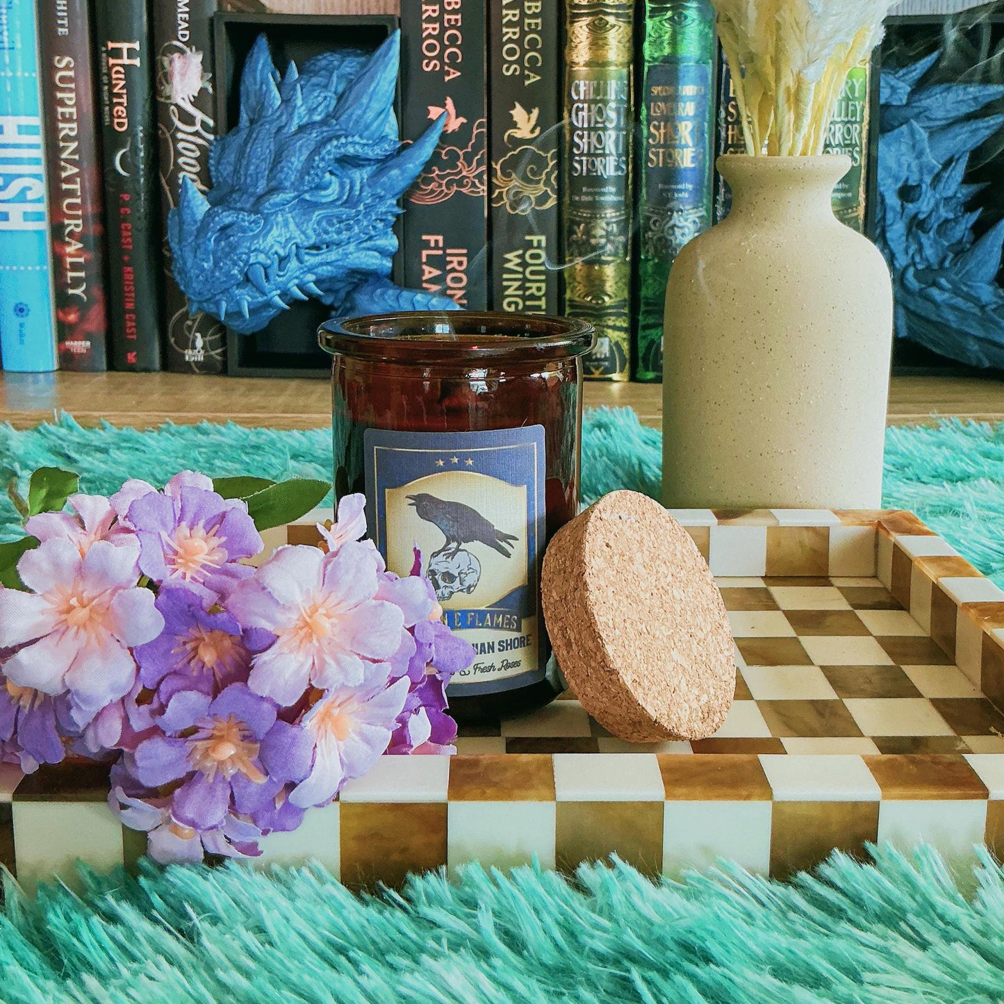 Nights Plutonian Shore Candle on chequered board with flowers