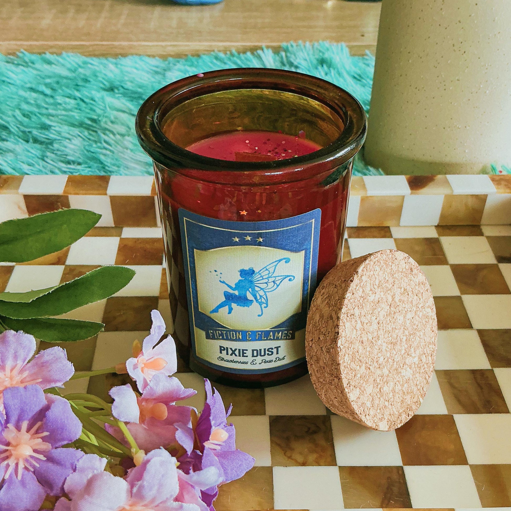 Pixie Dust Candle on a chequered board with flowers