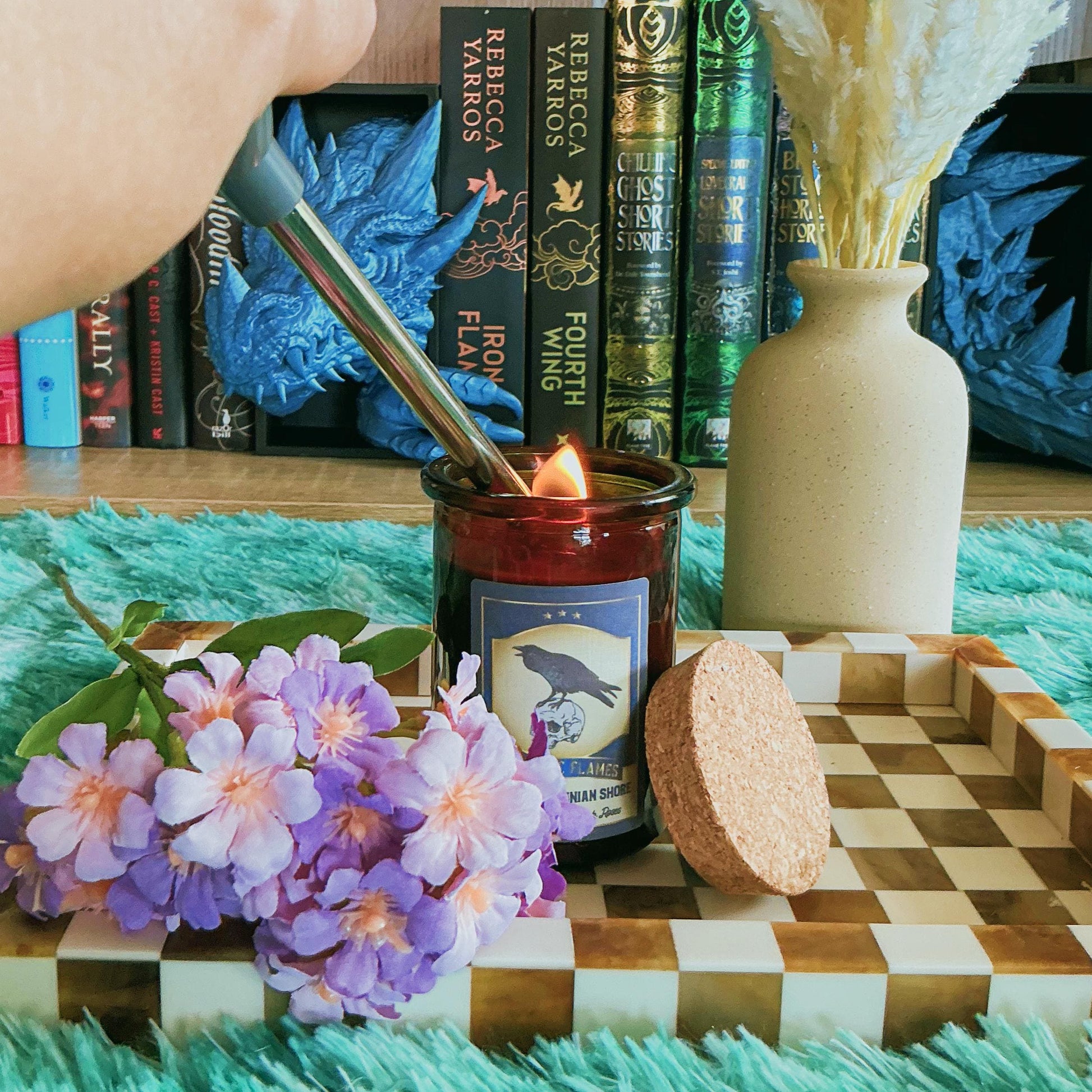 Nights Plutonian Shore Candle on chequered board with flowers