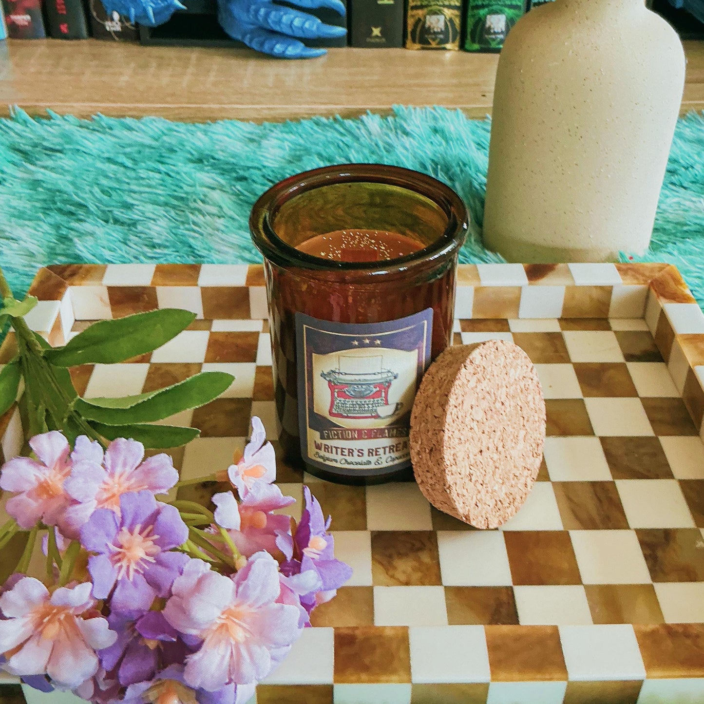 Writers Retreat candle on chequered board with flowers
